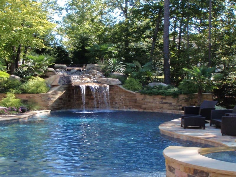 A pool waterfall over stonework among trees